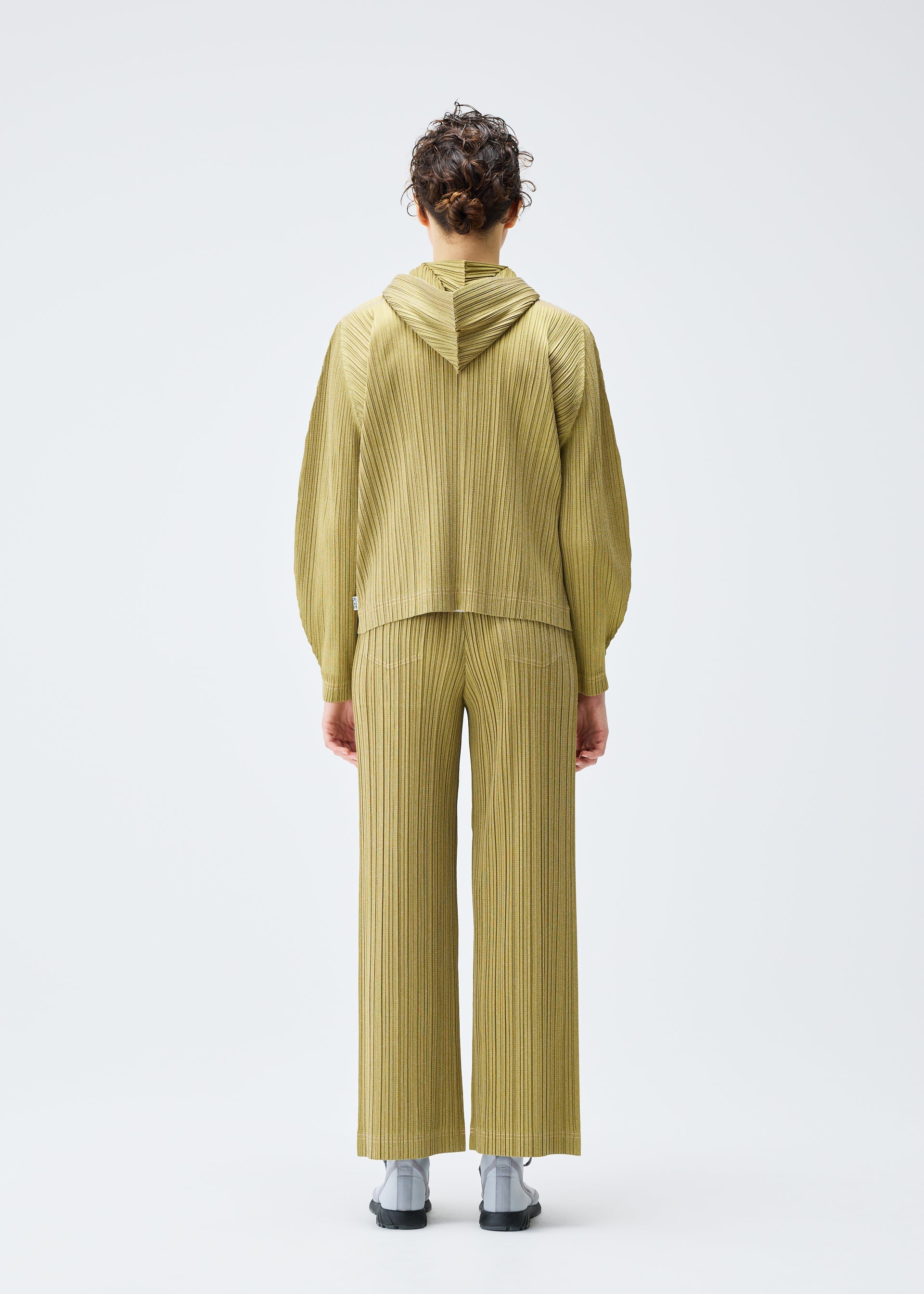 A model wears the PLEATS PLEASE ISSEY MIYAKE COTTON DENIM trousers.