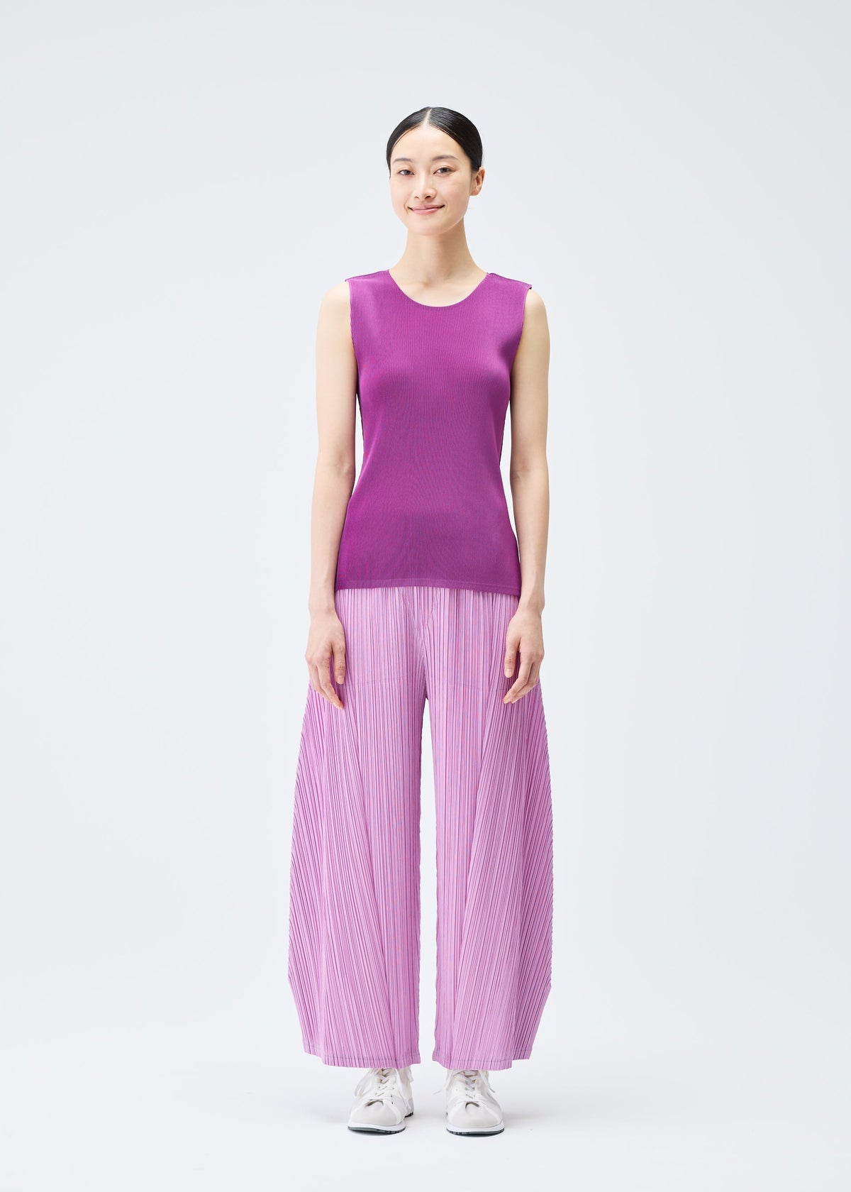 A model wears the Pleats Please Issey Miyake THICKER BOTTOMS 2 trousers.