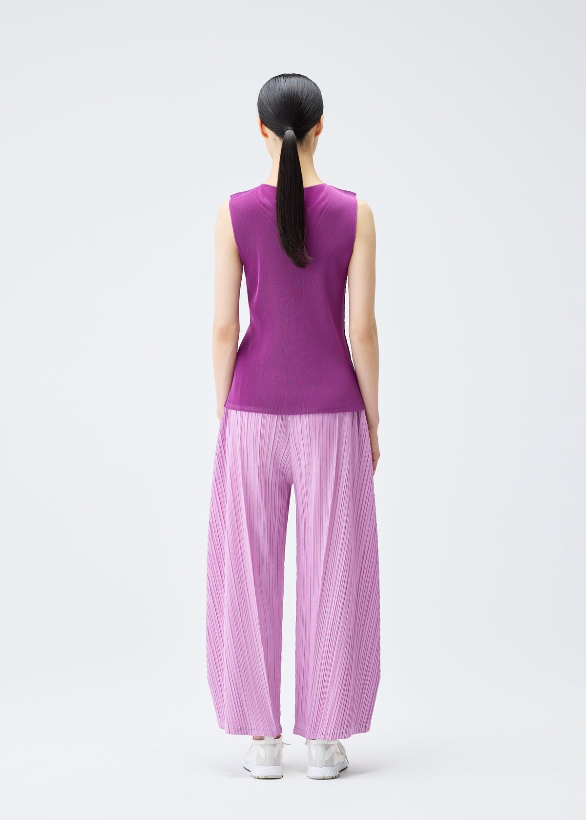 A model wears the Pleats Please Issey Miyake THICKER BOTTOMS 2 trousers.