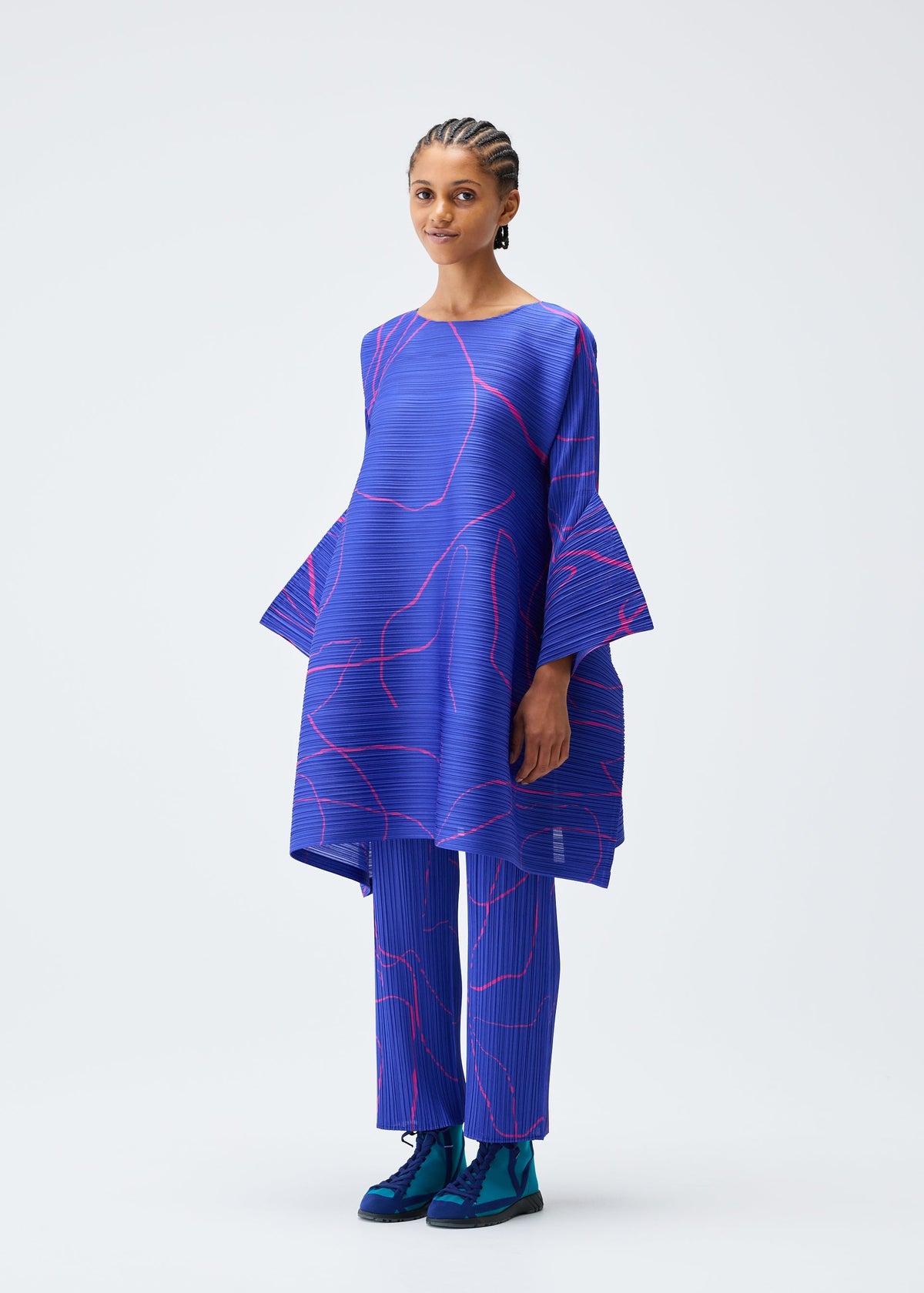 A model wears the Pleats Please Issey Miyake PAUSE trousers.