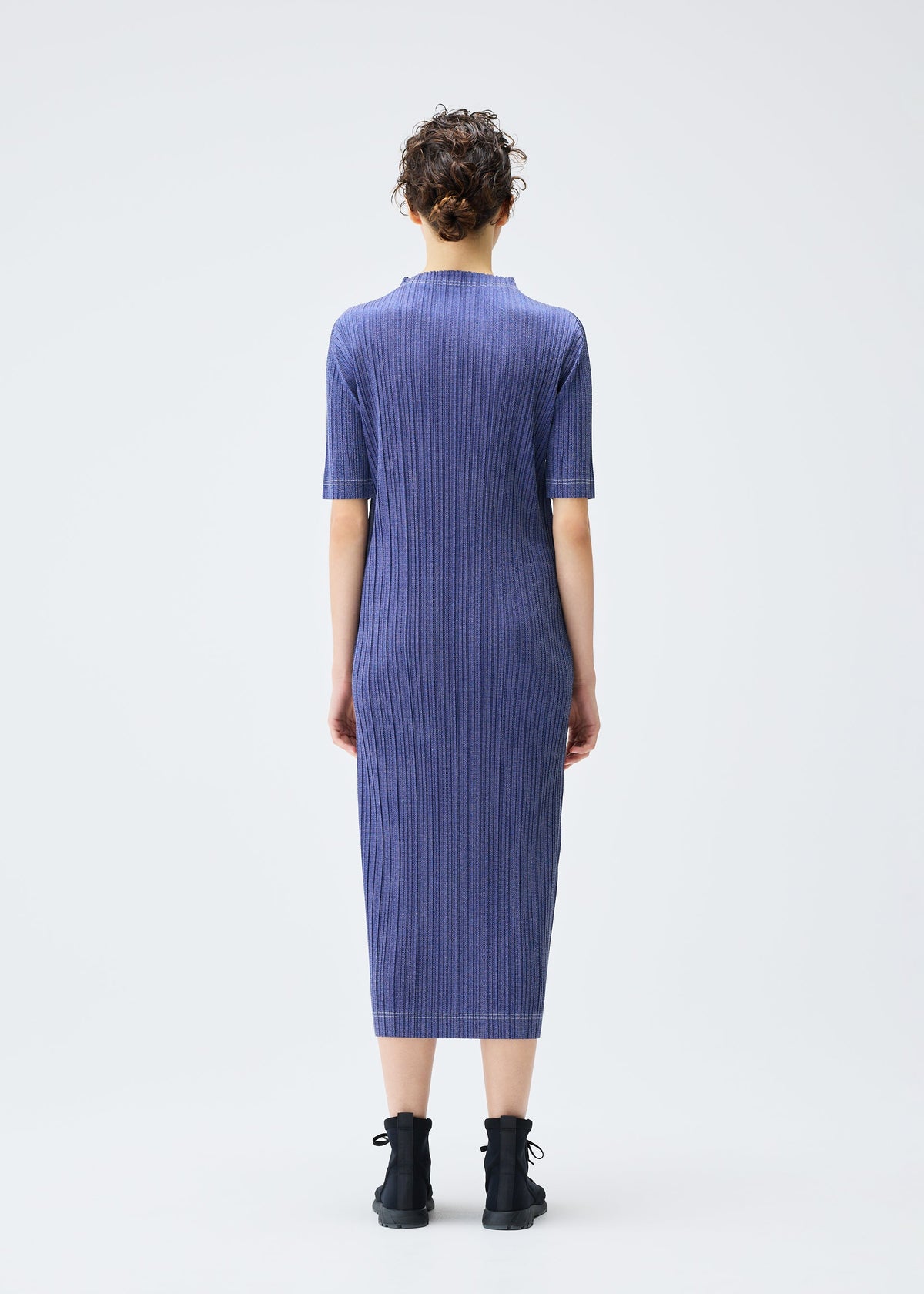 A model wears the PLEATS PLEASE ISSEY MIYAKE COTTON DENIM dress.