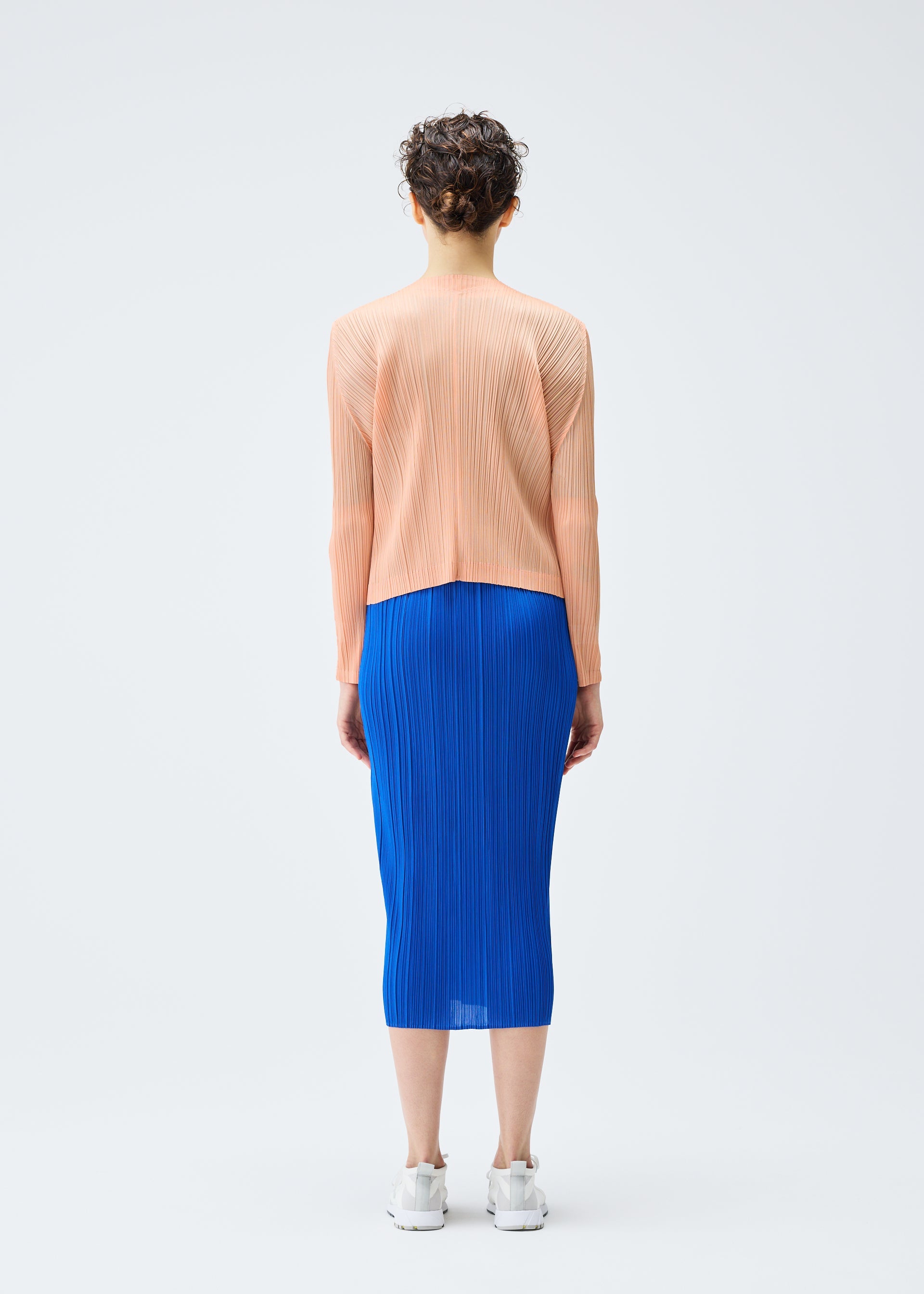 A model wears the PLEATS PLEASE ISSEY MIYAKE MONTHLY COLORS AUGUST cardigan.