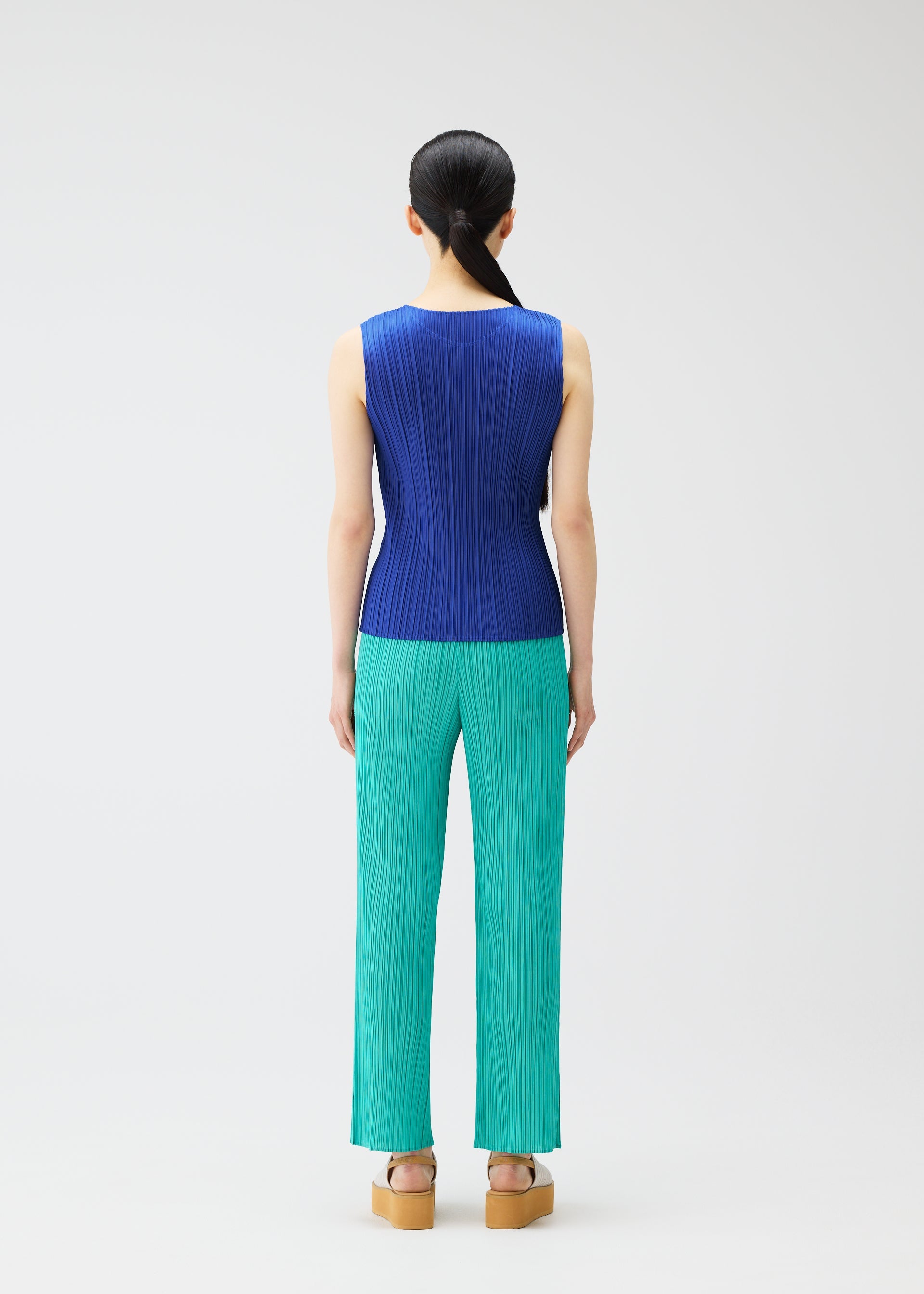 A model wears the Pleats Please Issey Miyake MONTHLY COLORS MAY trousers.
