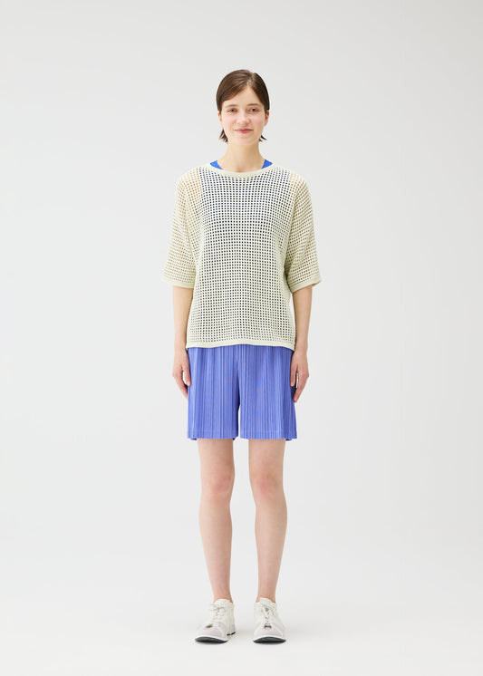 A model wears the Pleats Please Issey Miyake LOOP BOTTOMS trousers.