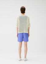 A model wears the Pleats Please Issey Miyake LOOP BOTTOMS trousers.