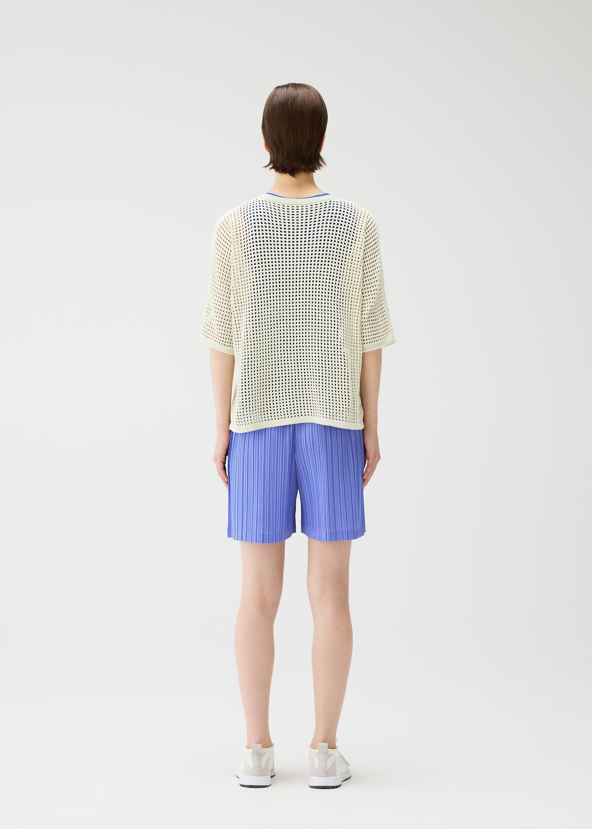 A model wears the Pleats Please Issey Miyake LOOP BOTTOMS trousers.