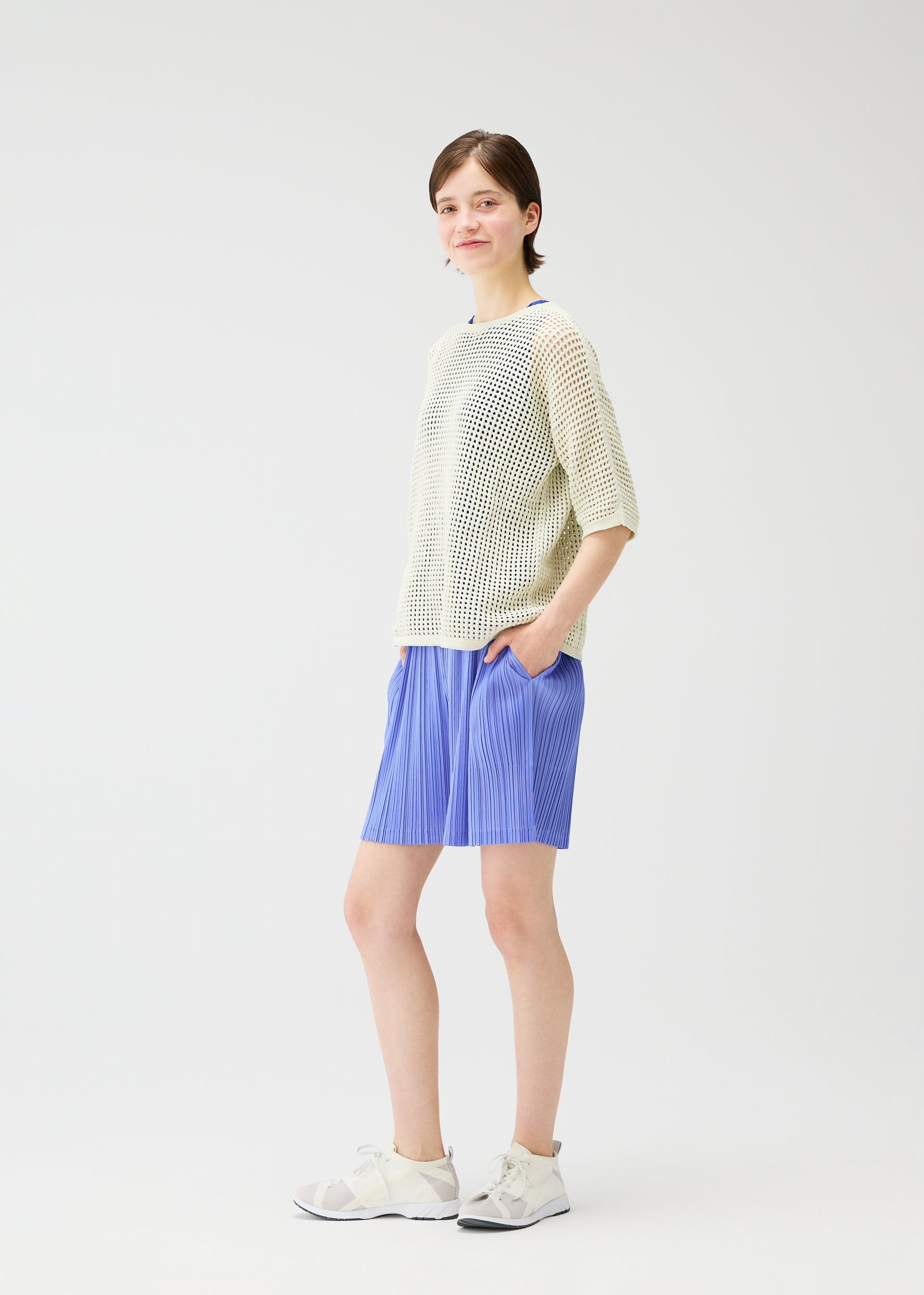 A model wears the Pleats Please Issey Miyake LOOP BOTTOMS trousers.
