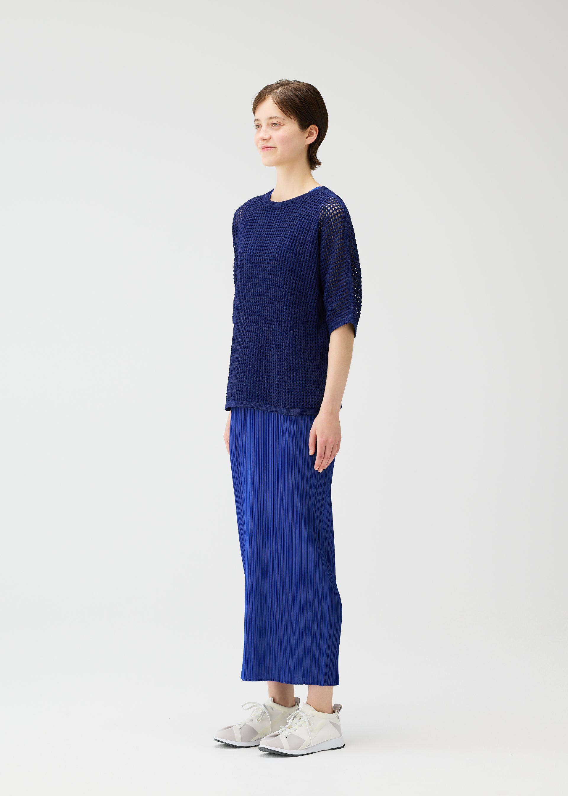 A model wears the Pleats Please Issey Miyake FISHNET KNIT shirt.