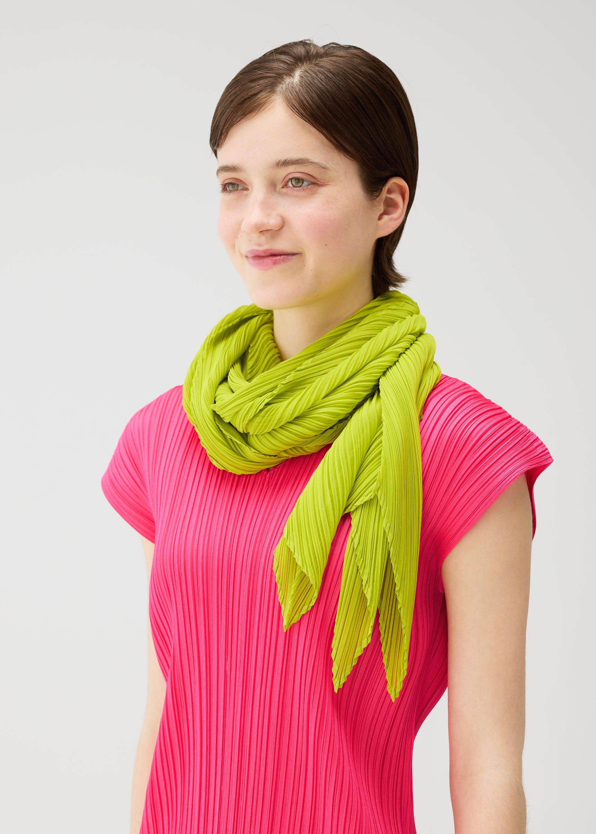 A model wears the PLEATS PLEASE ISSEY MIYAKE MONTHLY SCARF JUNE monthly-scarf-june-stole-bright-pink.
