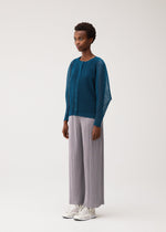 A model wears the PLEATS PLEASE ISSEY MIYAKE TATAMI AUGUST tatami-august-cardigan-greyish-green.
