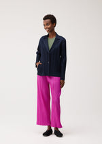 A model wears the PLEATS PLEASE ISSEY MIYAKE PLEATS JACKET jacket.