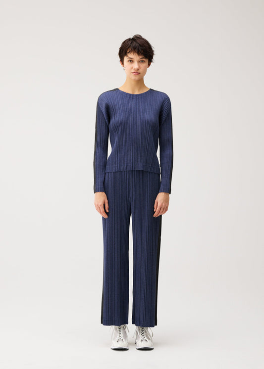 A model wears the PLEATS PLEASE ISSEY MIYAKE COTTON DENIM trousers.
