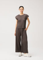A model wears the PLEATS PLEASE ISSEY MIYAKE MELLOW PLEATS trousers.