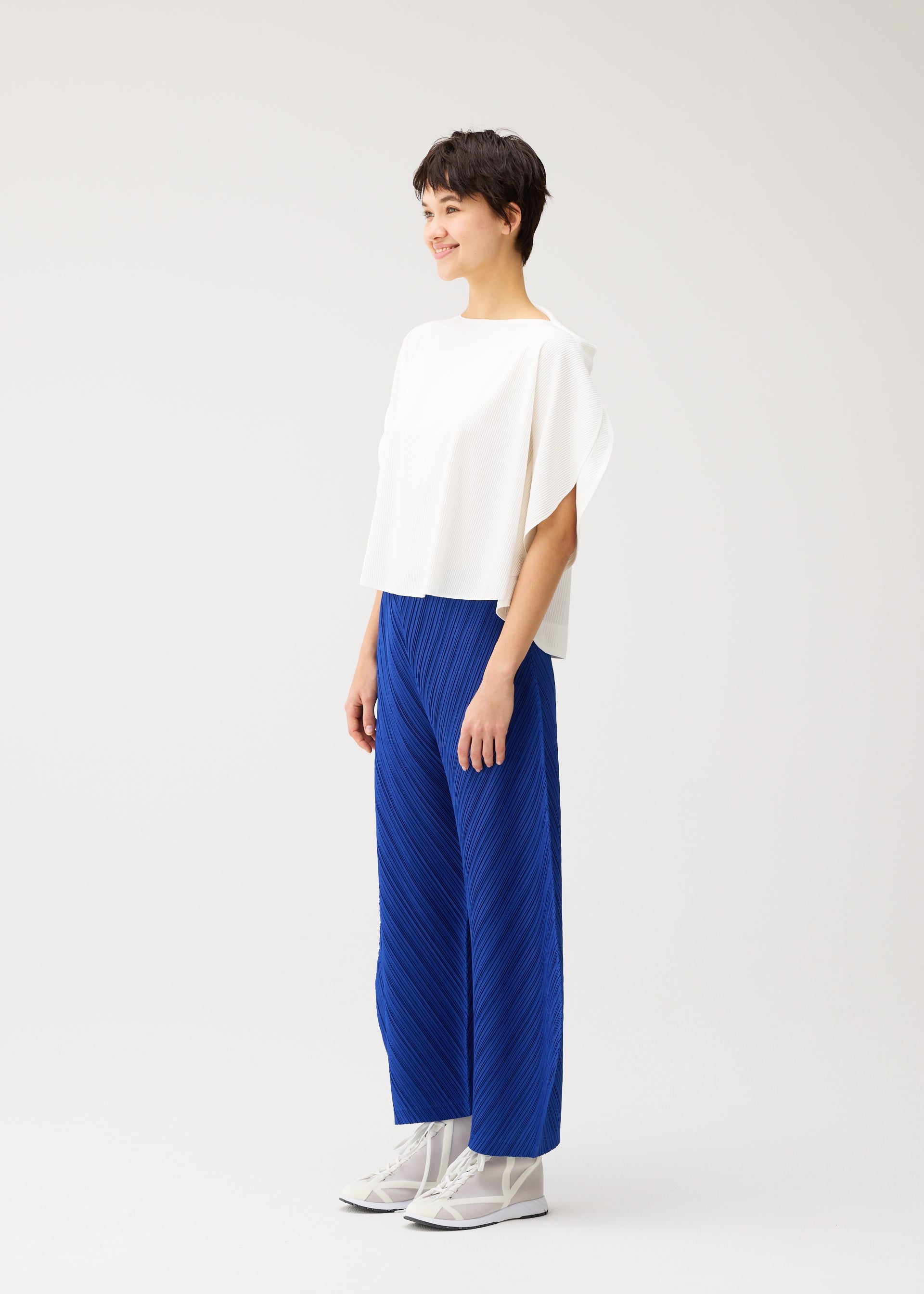 A model wears the PLEATS PLEASE ISSEY MIYAKE THICKER BOTTOMS 1 thicker-bottoms-1-trousers-1blue-2.