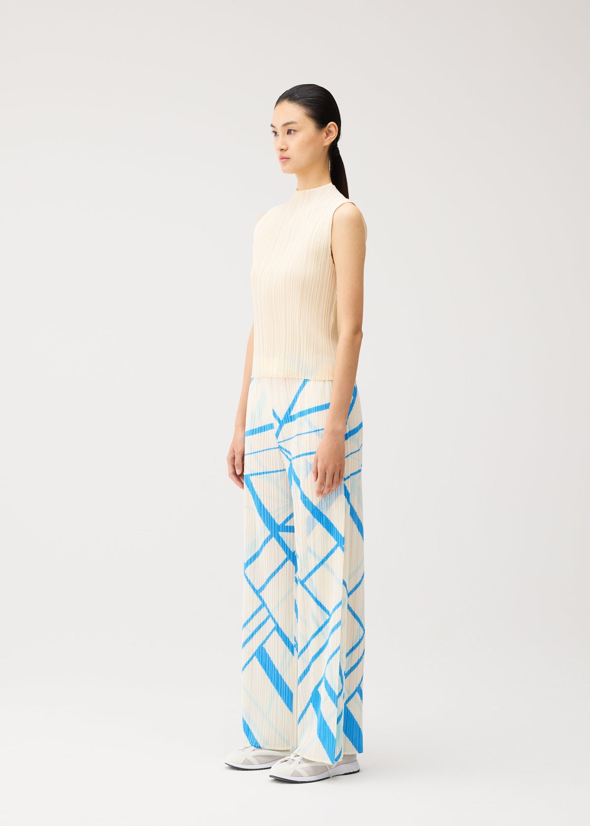 A model wears the PLEATS PLEASE ISSEY MIYAKE FOLD LINE fold-line-trousers-charcoal.