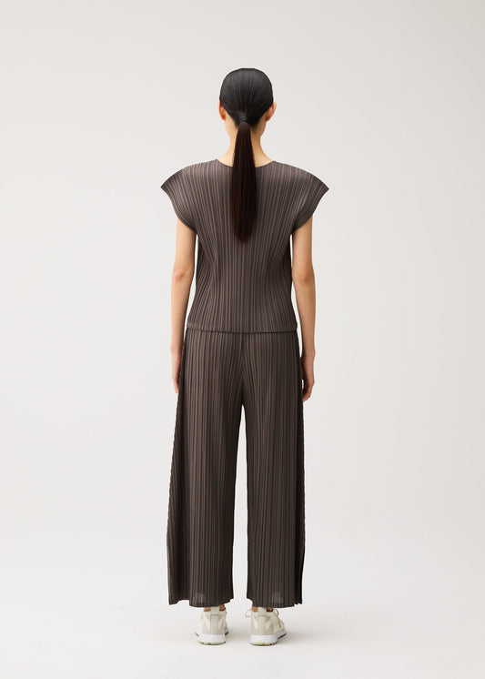 A model wears the PLEATS PLEASE ISSEY MIYAKE MELLOW PLEATS shirt.