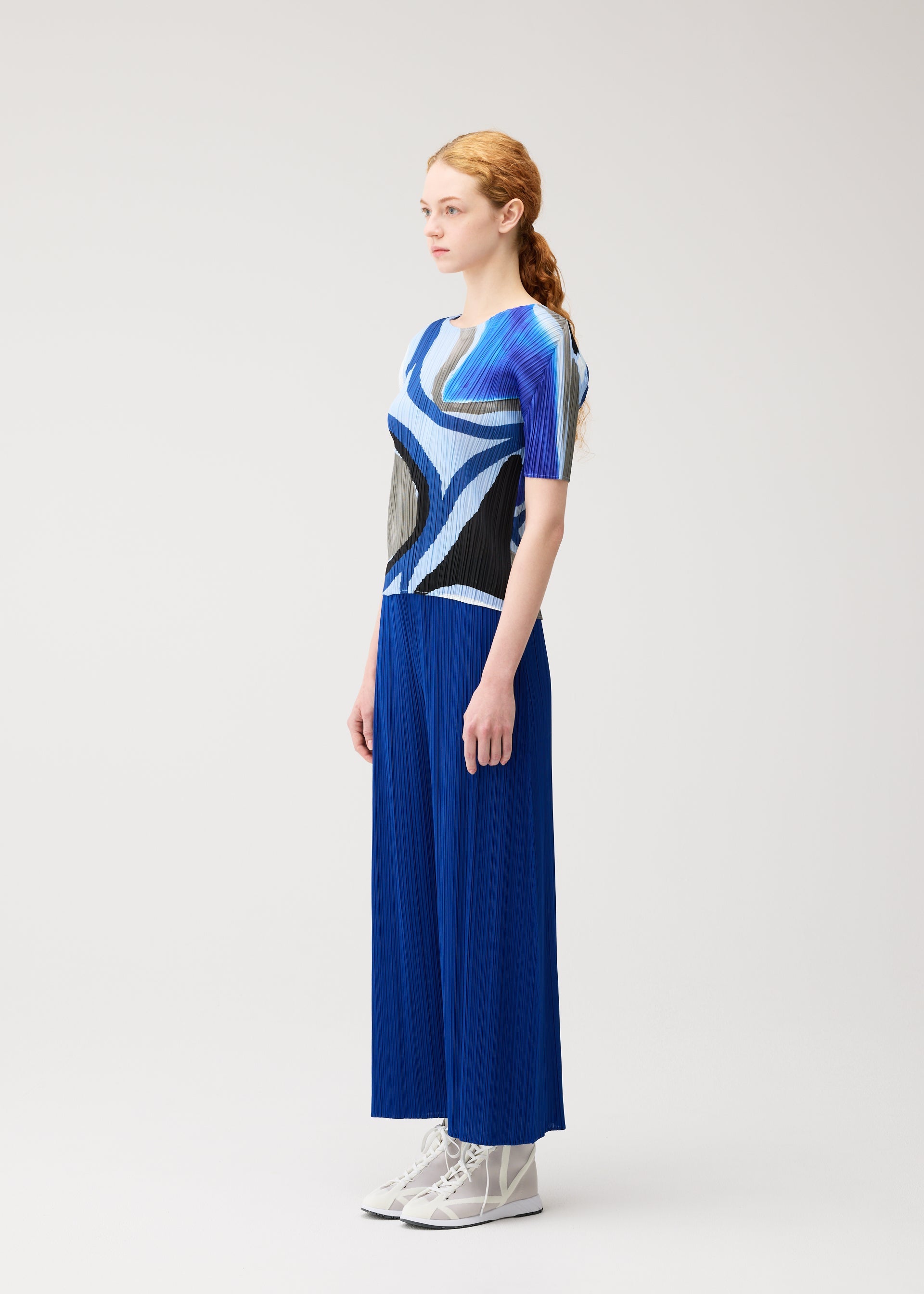 A model wears the PLEATS PLEASE ISSEY MIYAKE ROLL roll-shirt-light-blue.