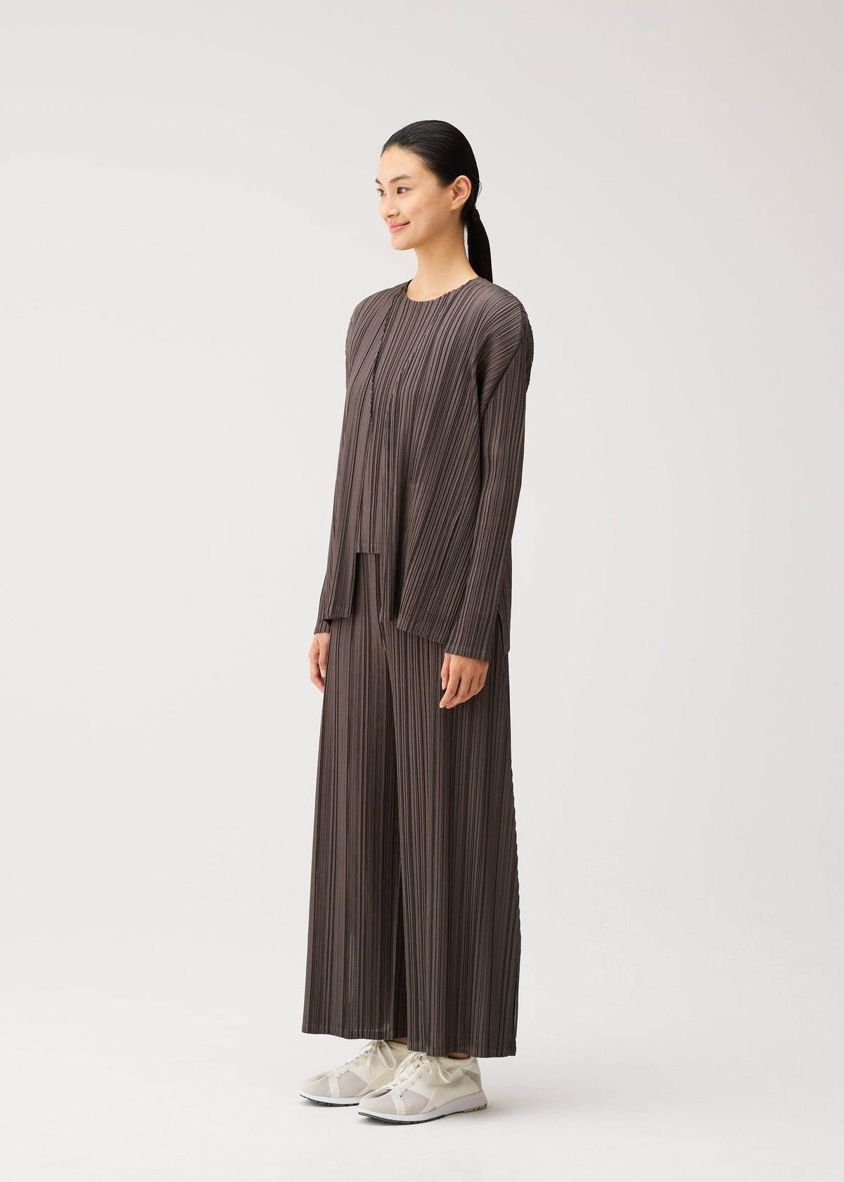 A model wears the PLEATS PLEASE ISSEY MIYAKE MELLOW PLEATS cardigan.