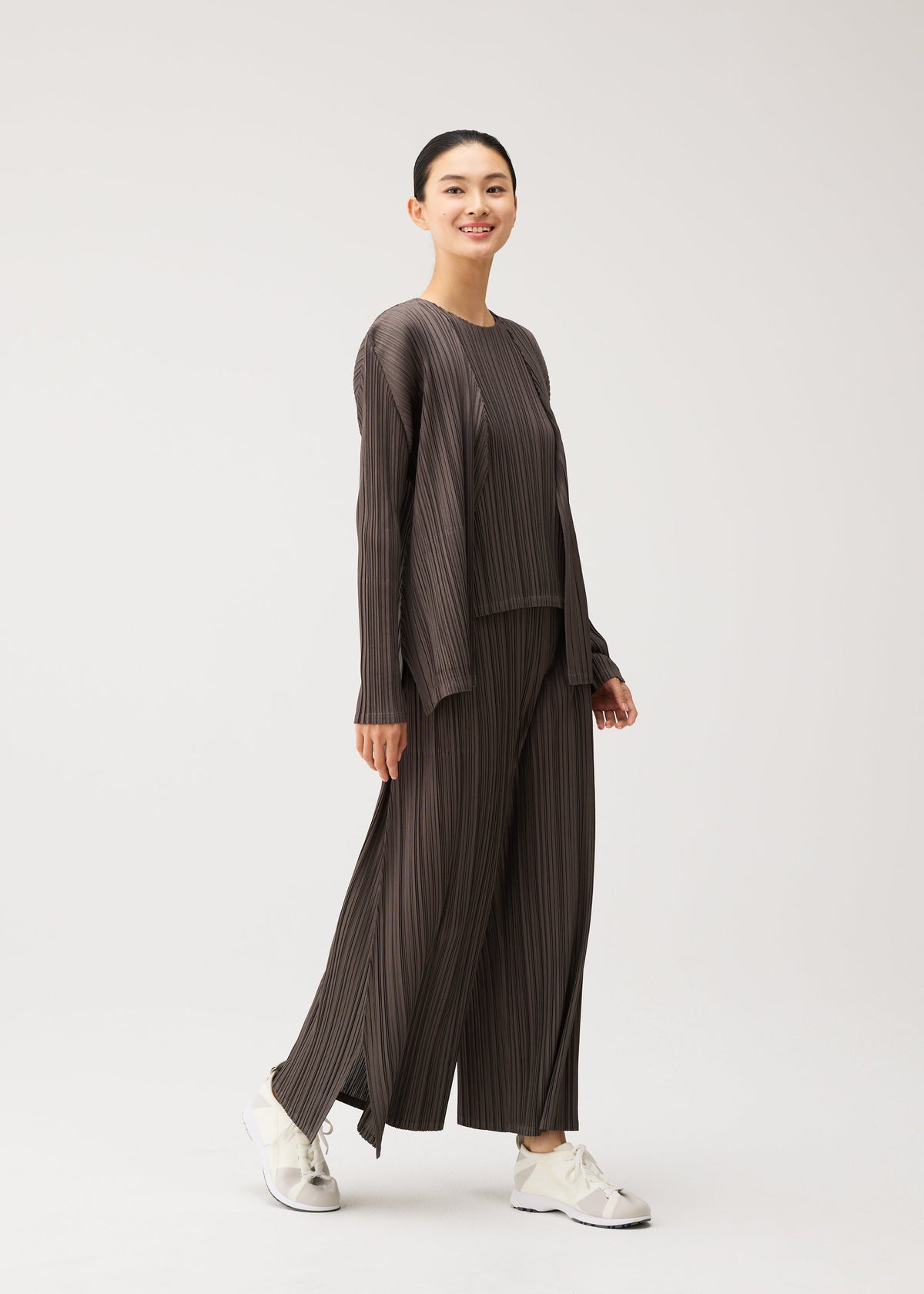 A model wears the PLEATS PLEASE ISSEY MIYAKE MELLOW PLEATS cardigan.