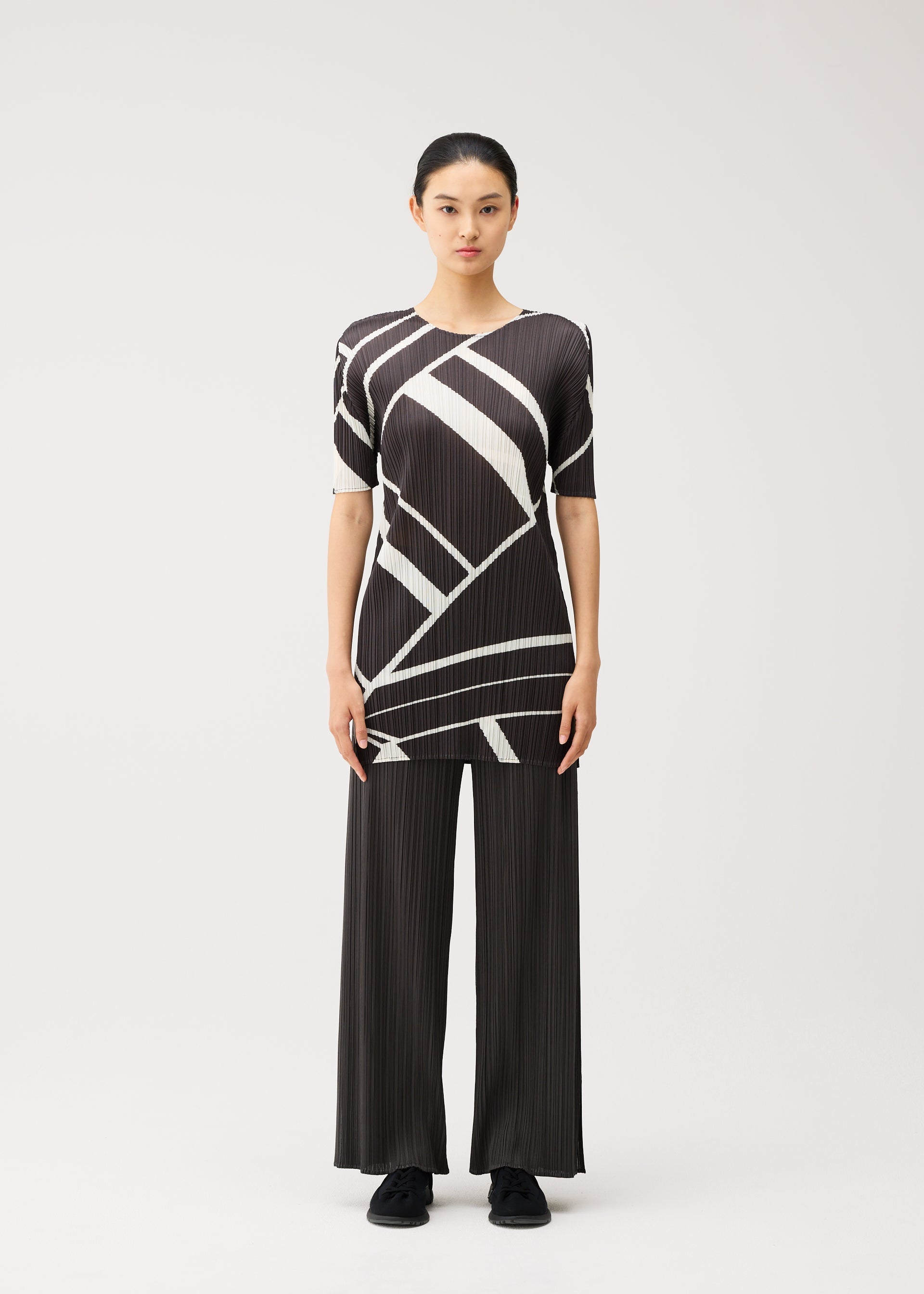 A model wears the PLEATS PLEASE ISSEY MIYAKE FOLD LINE fold-line-dress-off-white-1.