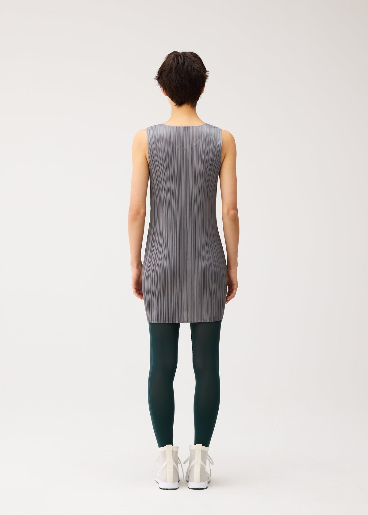 A model wears the PLEATS PLEASE ISSEY MIYAKE A-POC SKIN trousers.