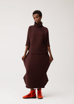 A model wears the PLEATS PLEASE ISSEY MIYAKE ZIG ZAG KNIT skirt.