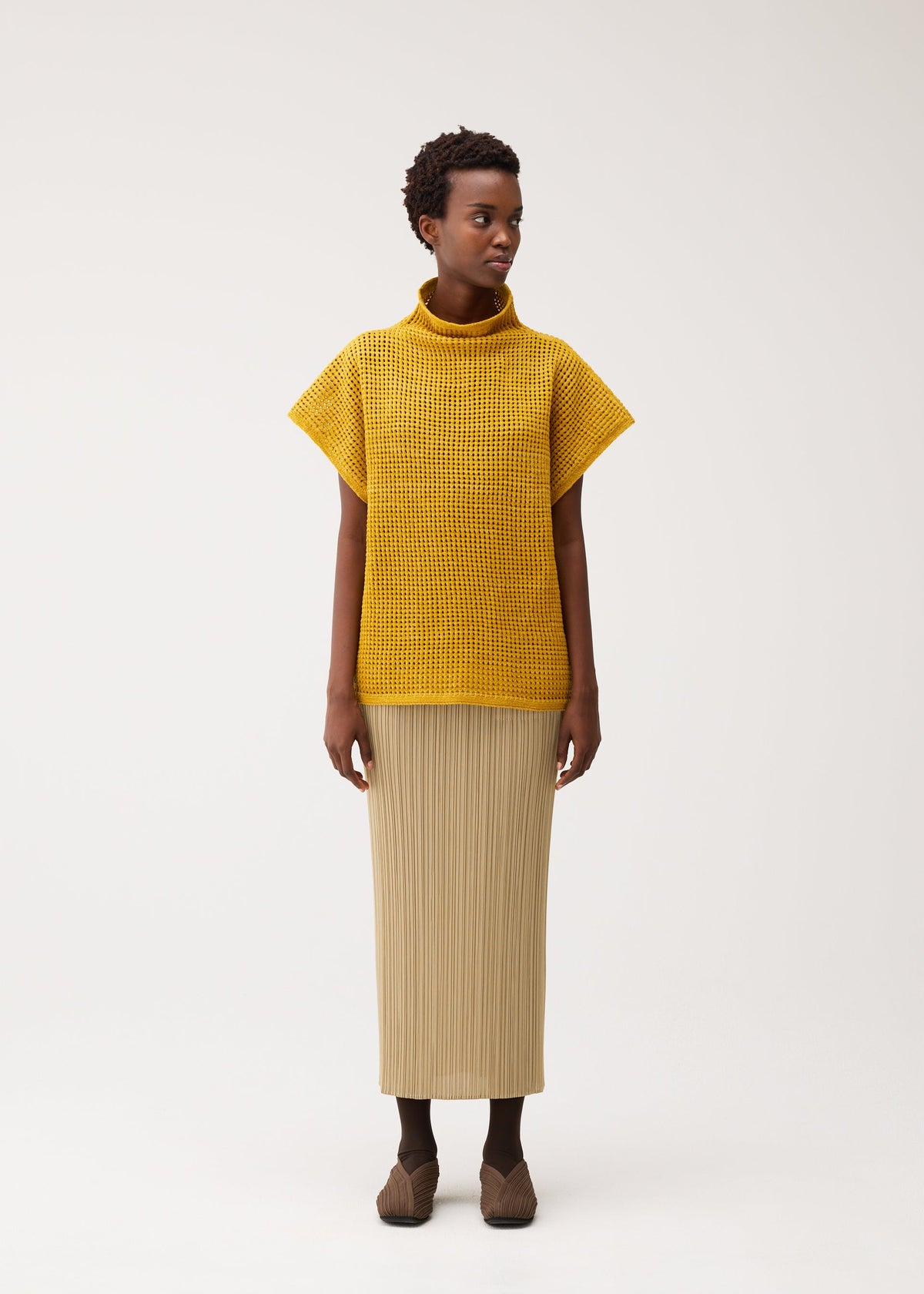 A model wears the PLEATS PLEASE ISSEY MIYAKE DOT KNIT dot-knit-shirt-ochre.