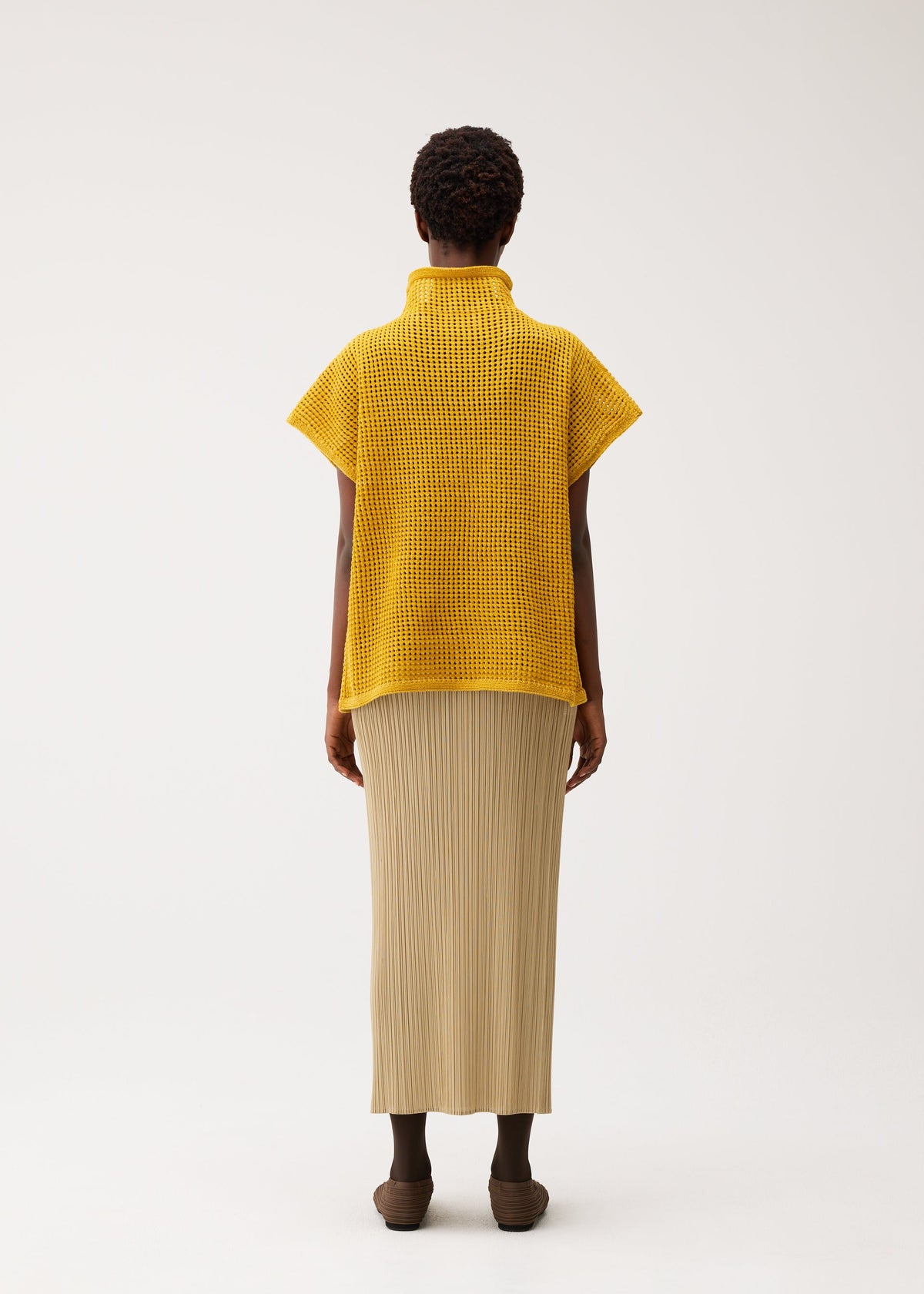 A model wears the PLEATS PLEASE ISSEY MIYAKE DOT KNIT shirt.