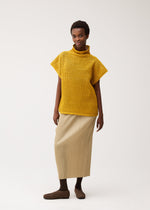 A model wears the PLEATS PLEASE ISSEY MIYAKE DOT KNIT shirt.
