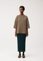 A model wears the PLEATS PLEASE ISSEY MIYAKE DOT KNIT dot-knit-shirt-ochre-1.