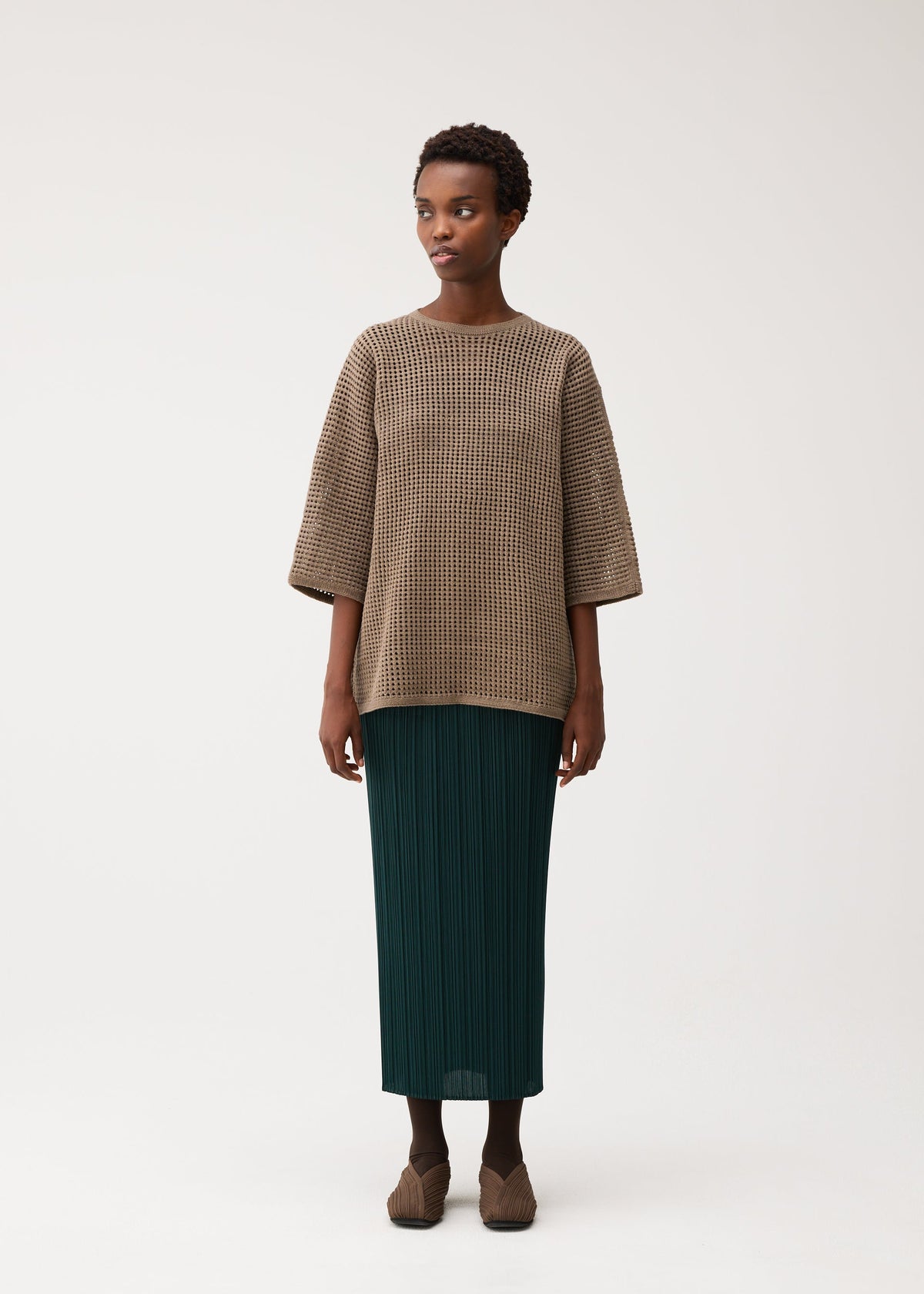 A model wears the PLEATS PLEASE ISSEY MIYAKE DOT KNIT dot-knit-shirt-ochre-1.