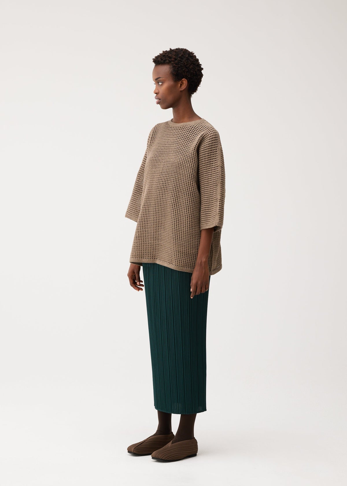 A model wears the PLEATS PLEASE ISSEY MIYAKE DOT KNIT shirt.