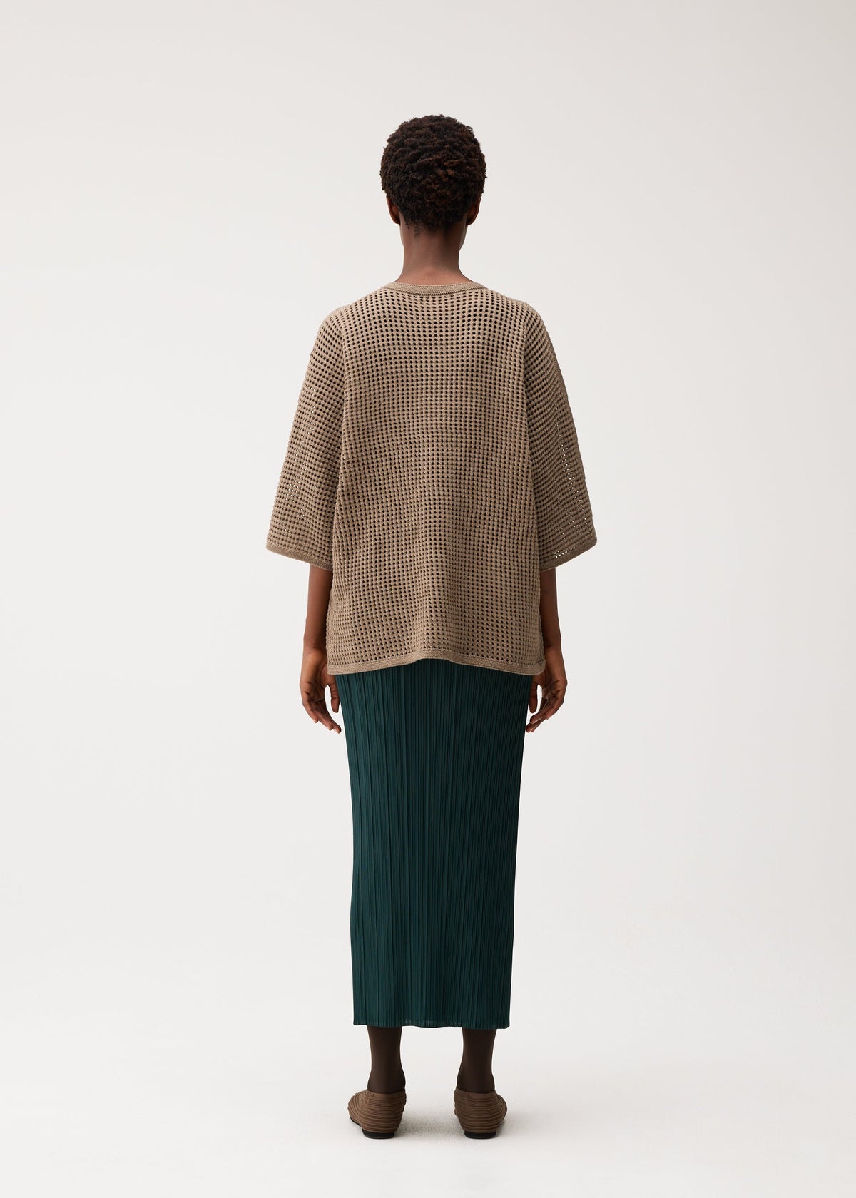 A model wears the PLEATS PLEASE ISSEY MIYAKE DOT KNIT shirt.