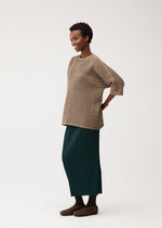 A model wears the PLEATS PLEASE ISSEY MIYAKE DOT KNIT shirt.