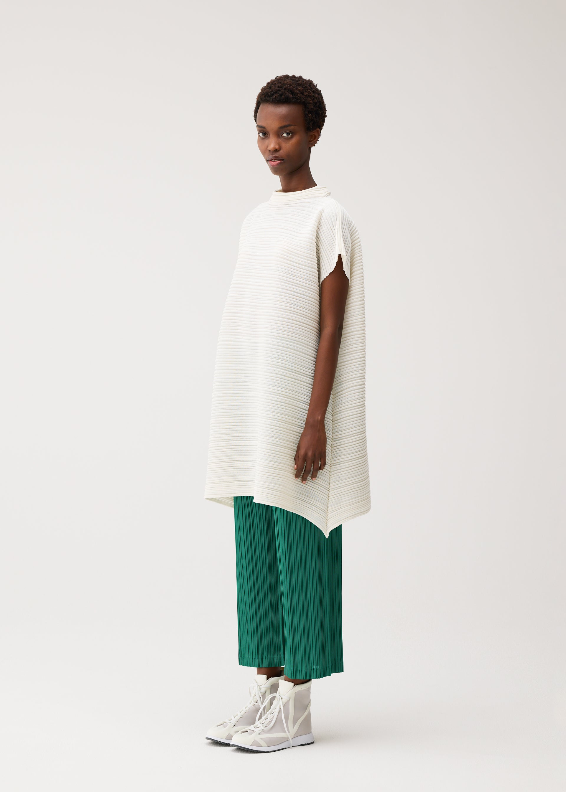 A model wears the PLEATS PLEASE ISSEY MIYAKE PAPER BOUNCE KNIT paper-bounce-knit-shirt-white-2.
