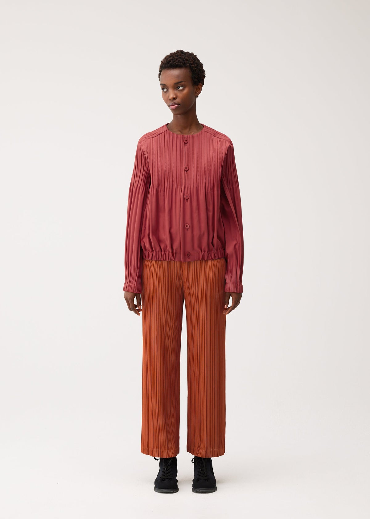 A model wears the PLEATS PLEASE ISSEY MIYAKE SMOOTH COAT coat.