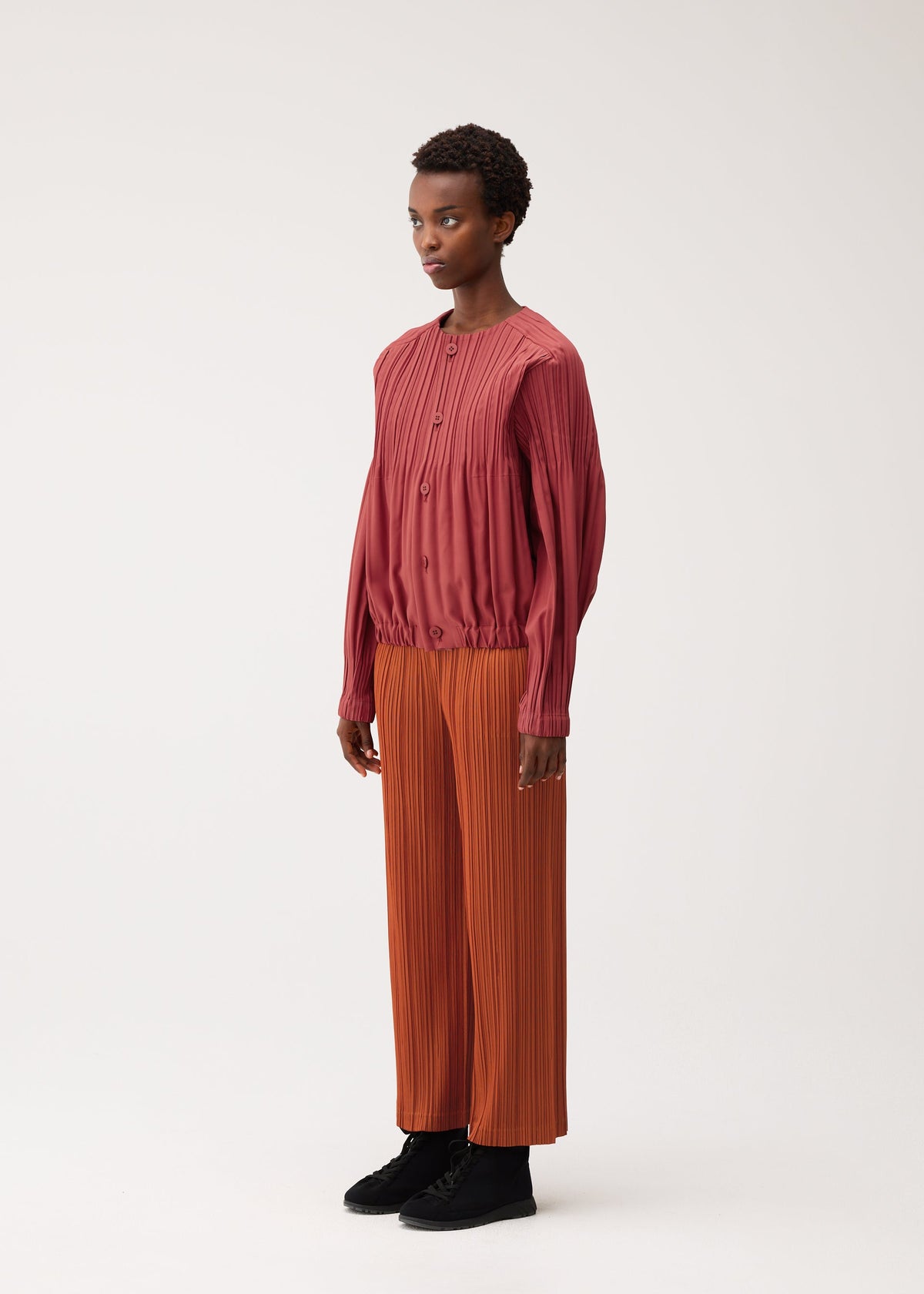 A model wears the PLEATS PLEASE ISSEY MIYAKE SMOOTH COAT coat.