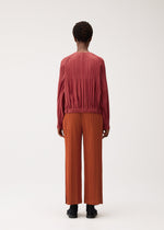 A model wears the PLEATS PLEASE ISSEY MIYAKE SMOOTH COAT coat.