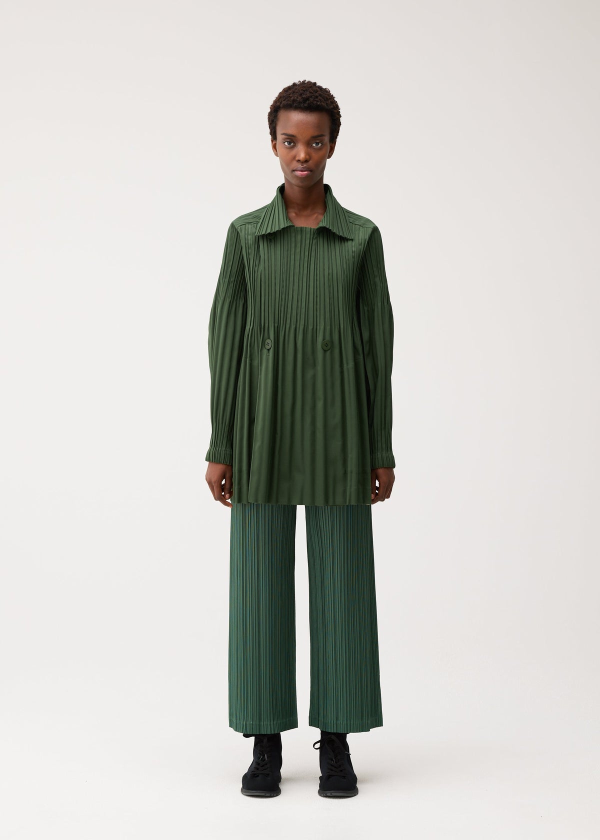 A model wears the PLEATS PLEASE ISSEY MIYAKE SMOOTH COAT coat.