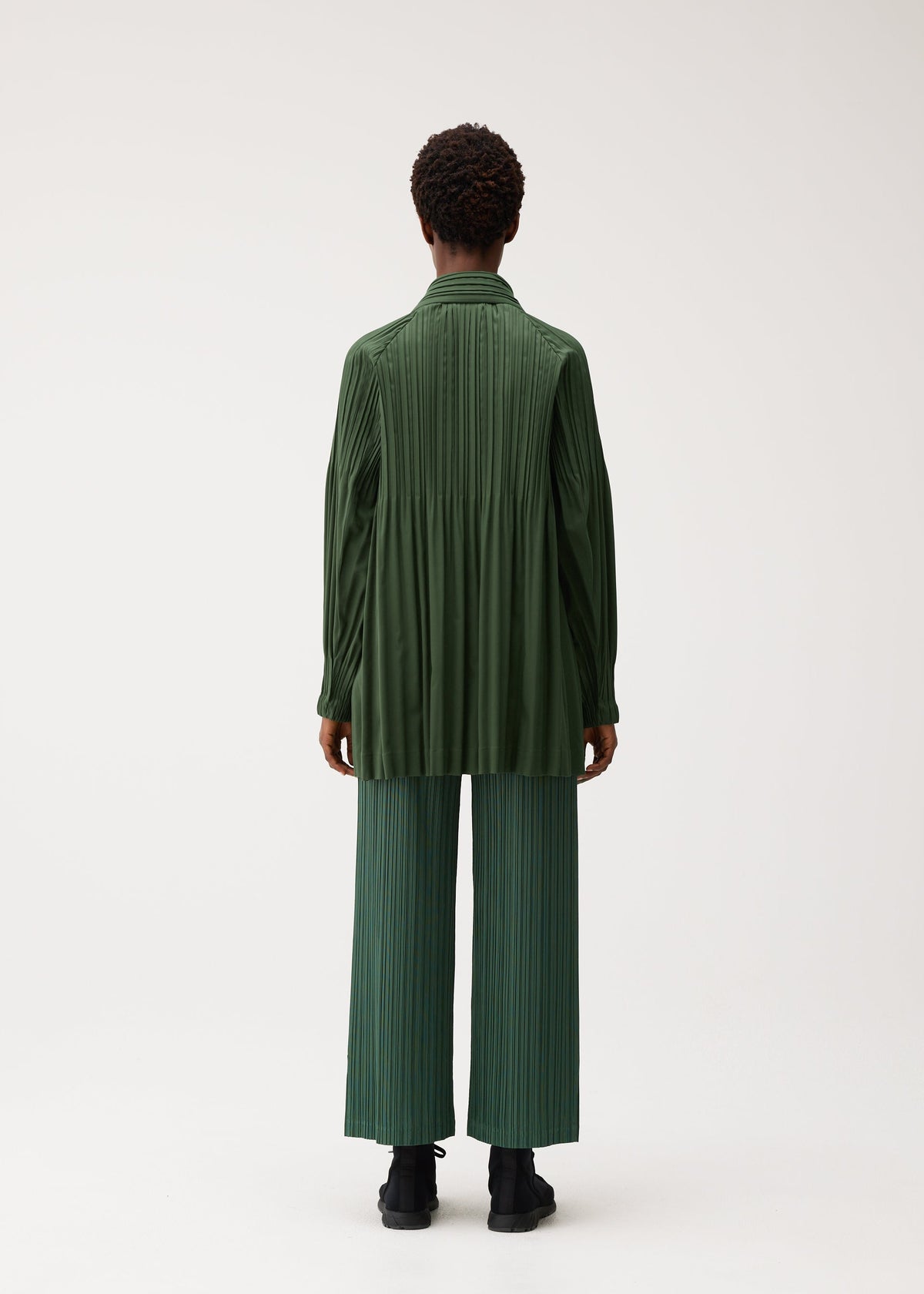 A model wears the PLEATS PLEASE ISSEY MIYAKE SMOOTH COAT coat.
