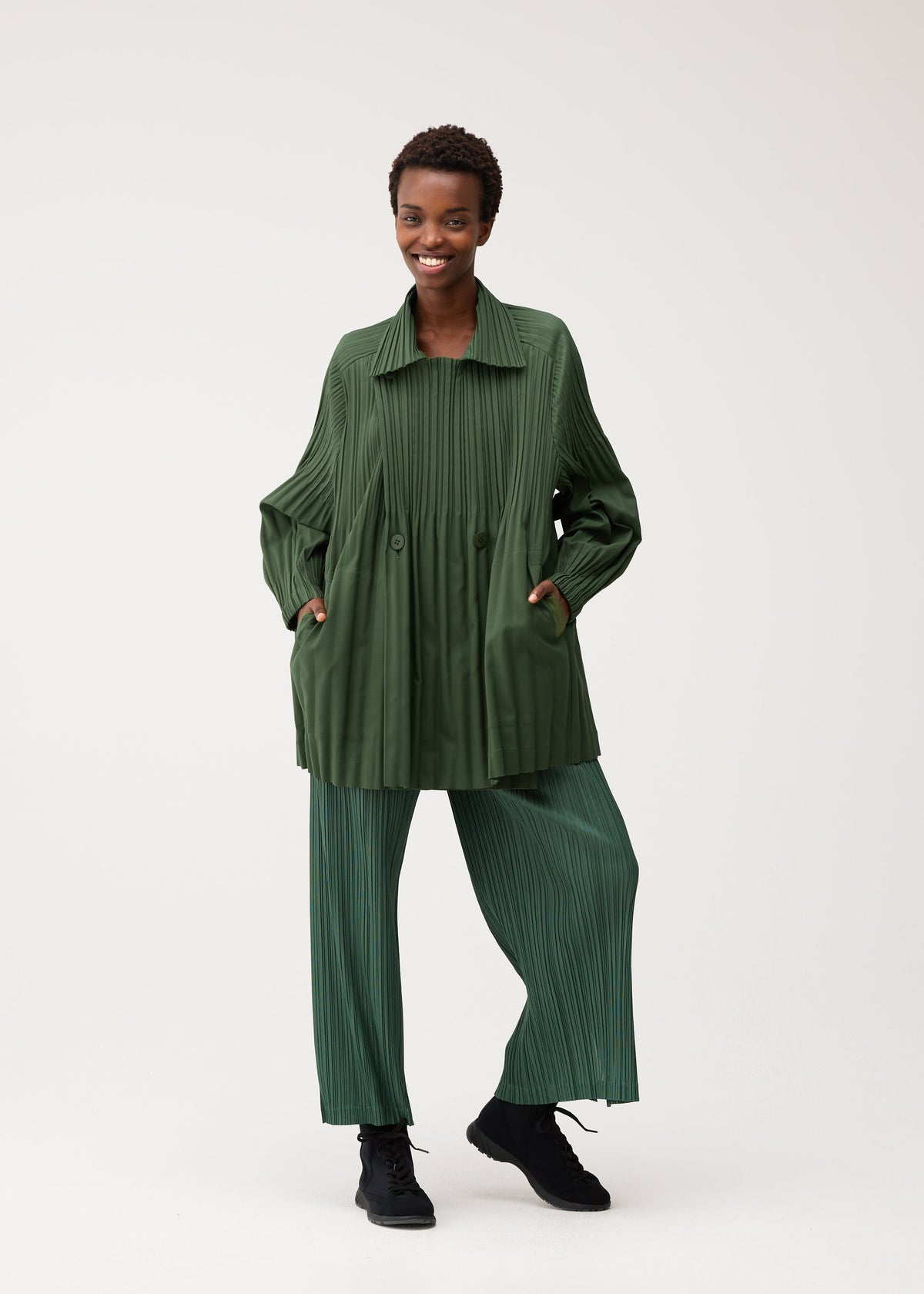 A model wears the PLEATS PLEASE ISSEY MIYAKE SMOOTH COAT coat.
