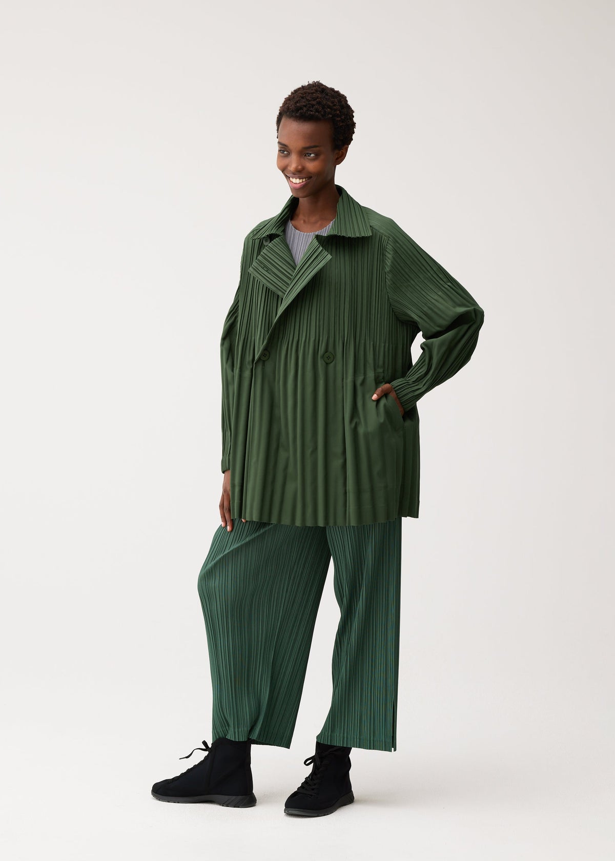A model wears the PLEATS PLEASE ISSEY MIYAKE SMOOTH COAT coat.