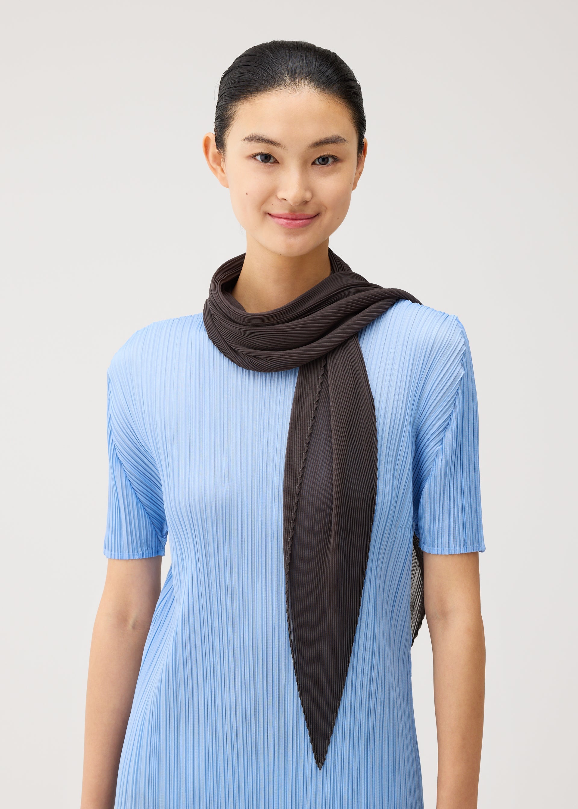A model wears the PLEATS PLEASE ISSEY MIYAKE MONTHLY SCARF AUGUST monthly-scarf-august-stole-charcoal.
