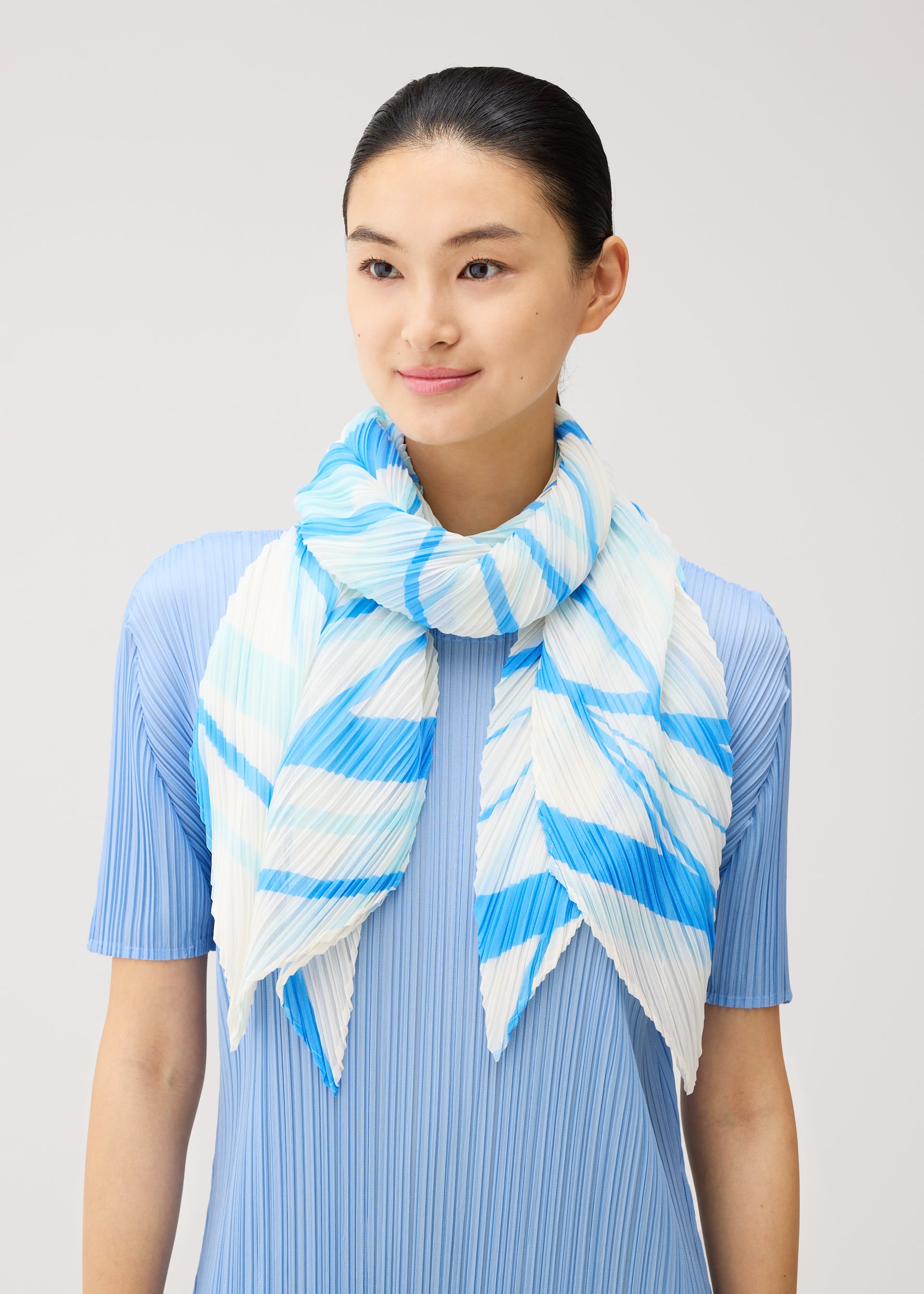 A model wears the PLEATS PLEASE ISSEY MIYAKE FOLD LINE SCARF fold-line-scarf-stole-off-white.