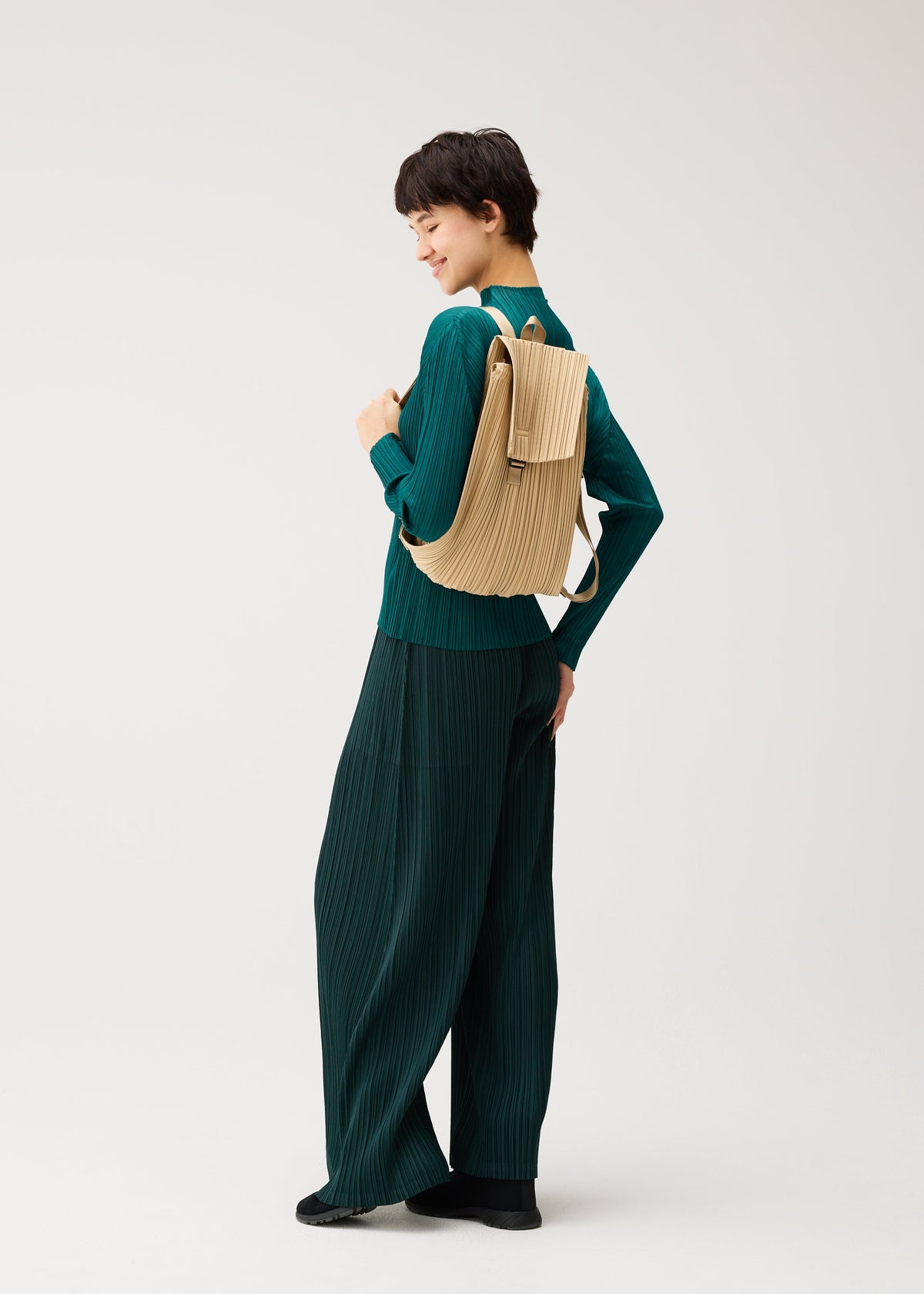 A model wears the PLEATS PLEASE ISSEY MIYAKE PLEATS KNAPSACK bag.